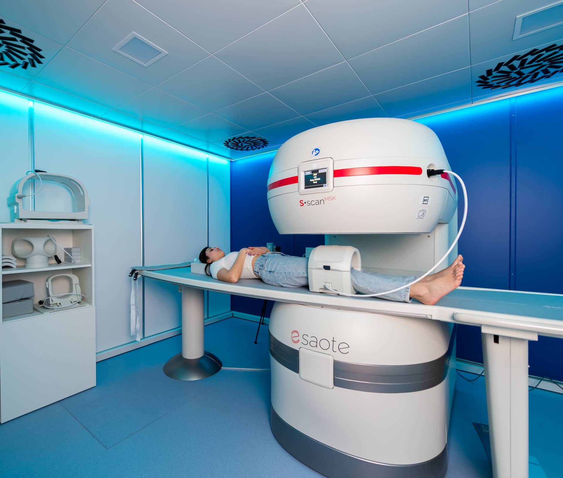 La sala della risonanza magnetica aperta di CF Medical Group: una paziente sdraiata sul lettino con il ginocchio dentro la macchina, testa e torace all'aria