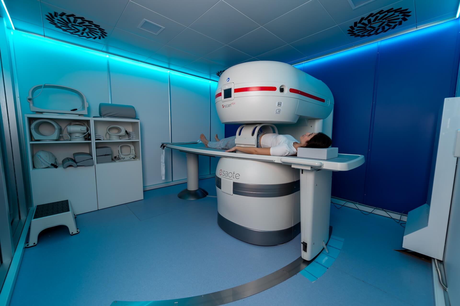 Paziente sdraiata sul lettino della risonanza magnetica aperta Esaote S-scan MSK: la testa e il torace restano fuori dalla macchina